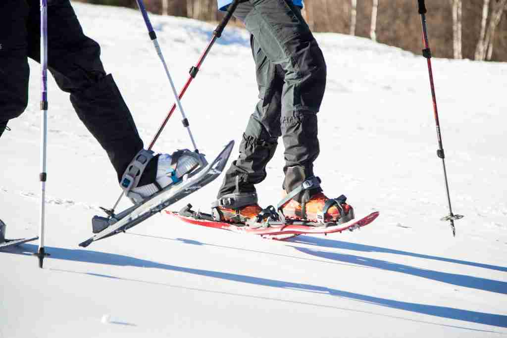Portrait of young couple walking in snowshoes over winter background.