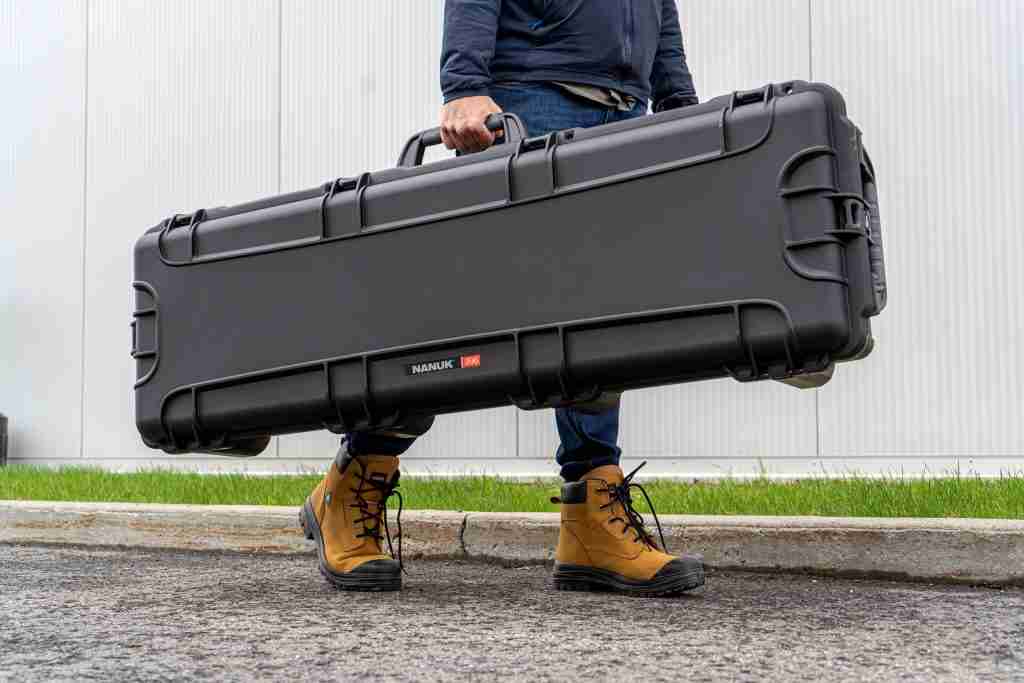 A man carries a Nanuk long gun case, one of the best portable gun safes & cases. 