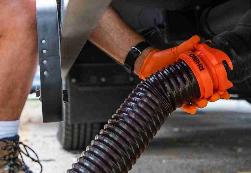Man utilizing a Rhino RV Sewer Adapter Pro on his RV to empty and sanitize holding tanks