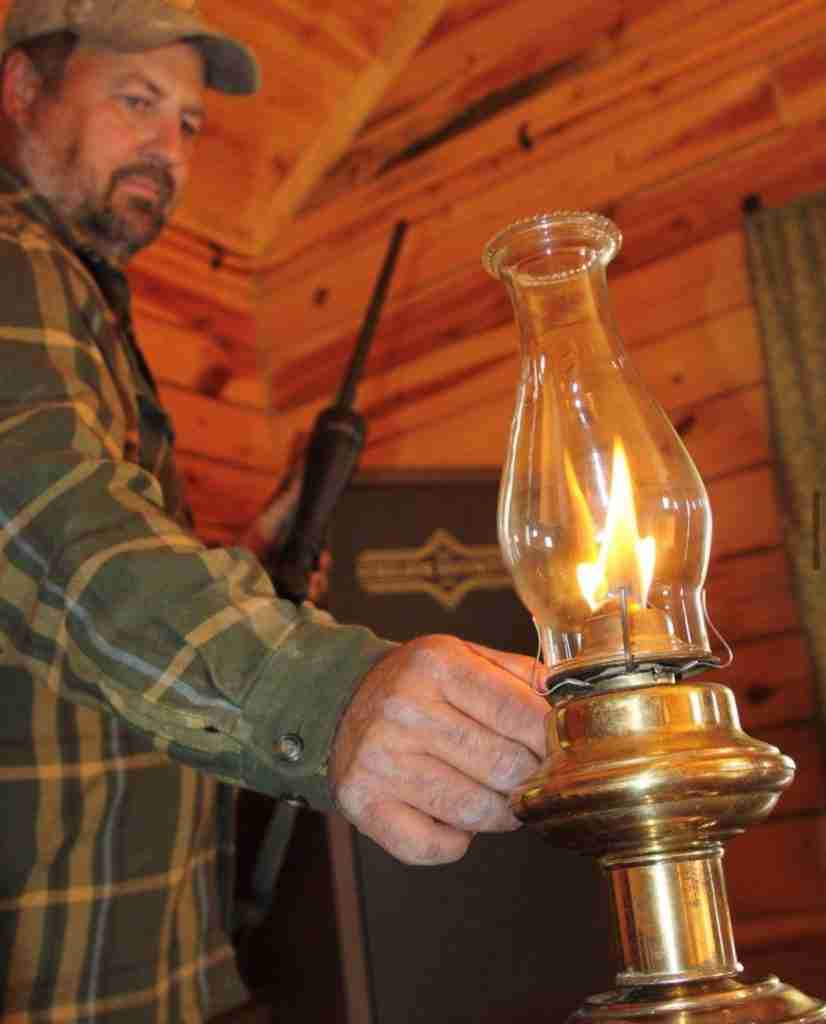 Man in log cabin with Surelock Utility Cabinet using a lamp to illuminate the area.