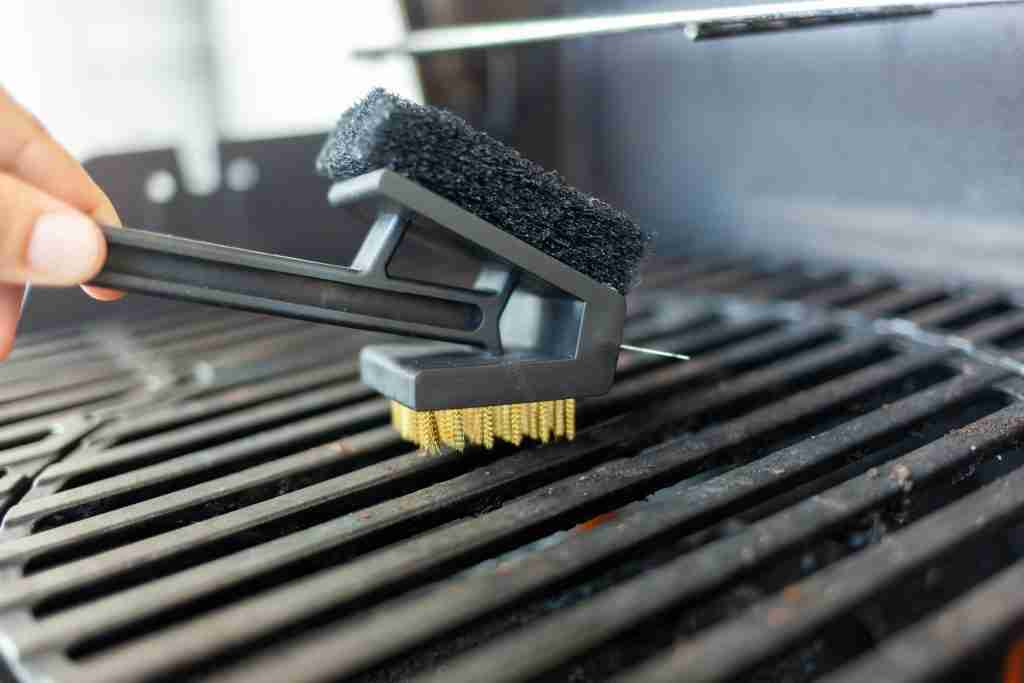 Grill master cleaning a barbecue grill with a wire bristle brush