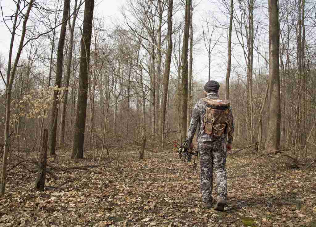 Man wears a bucket backpack while hunting in the woods