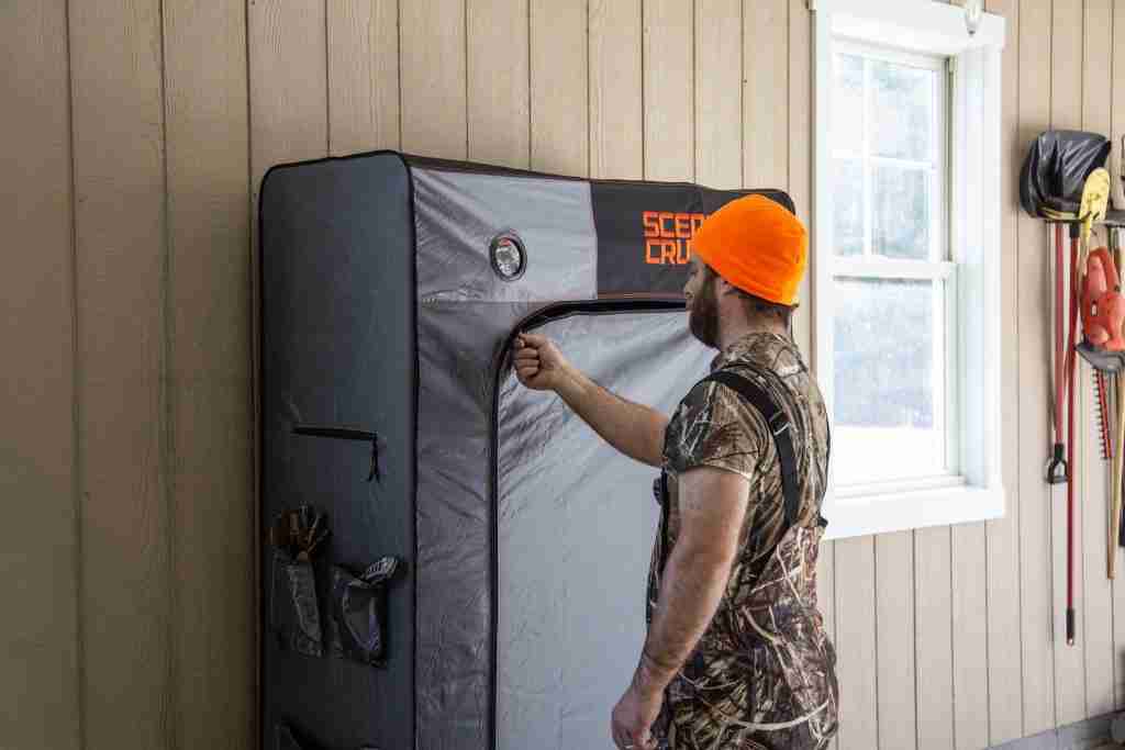 Man in camouflage shirt zips up a large scent crusher