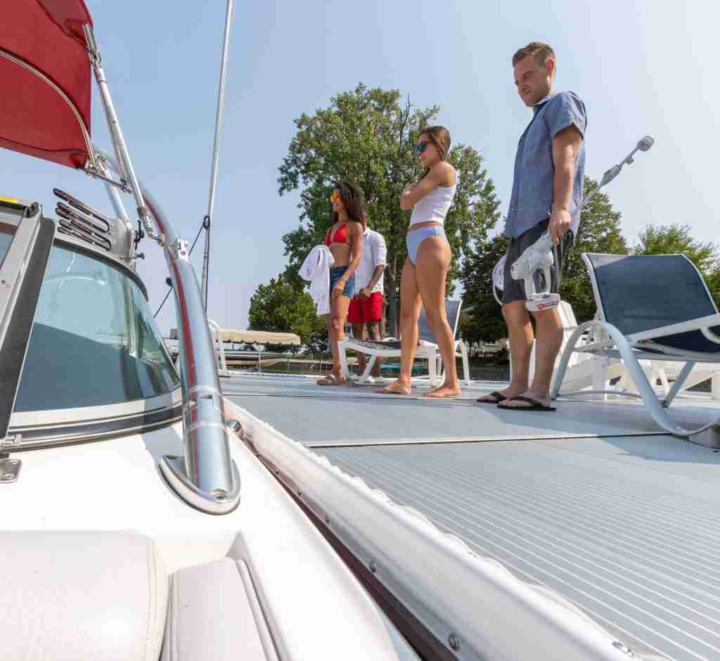 A family stands on a dock near a boat and dock bumper