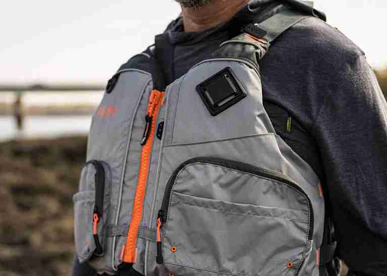 Man wearing a grey life jacket near a body of water