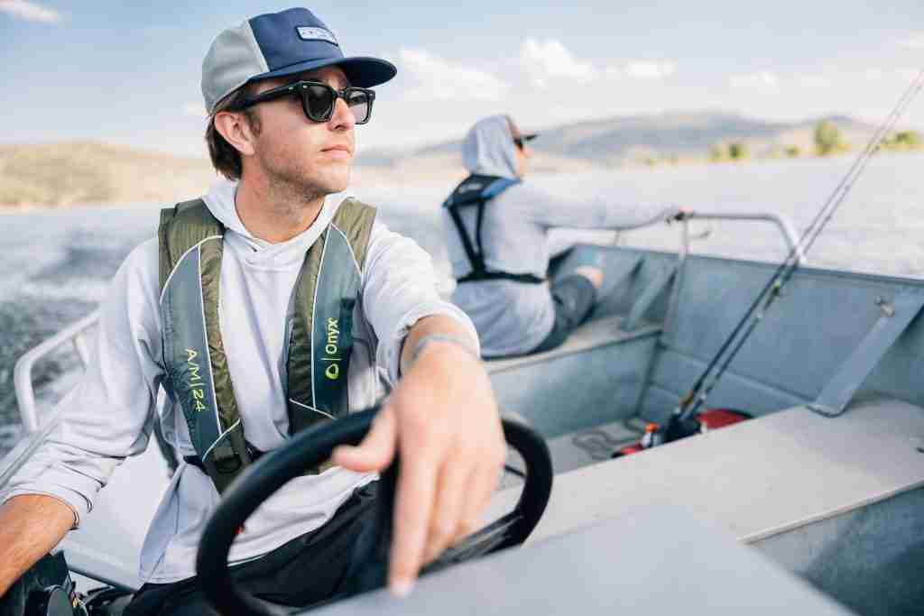 Man driving a boat while wearing an Onyx inflatable PFD